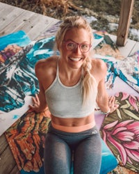 a woman in glasses is sitting on a yoga mat