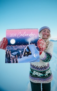 a woman holding up a calendar in the snow